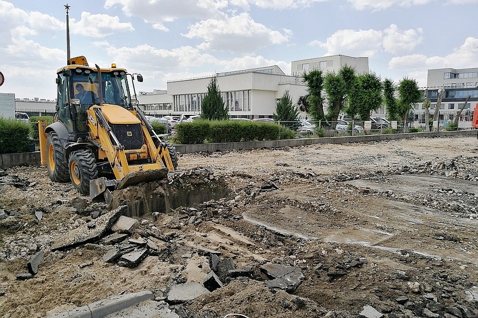 Техника выдирает старый асфальт с тротуара.
