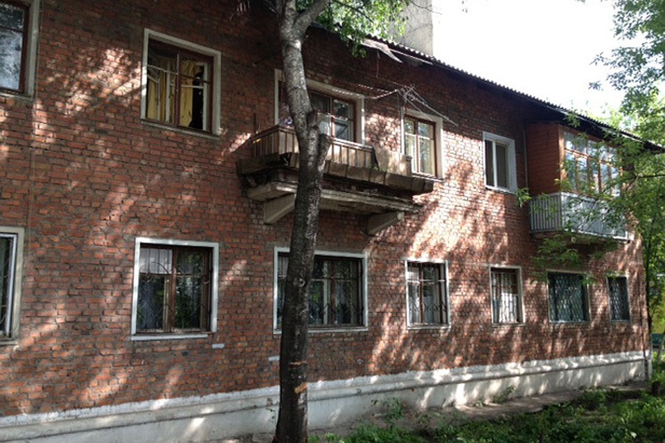 На разбитом окне на втором этаже развевается затрапезная желтая занавеска
