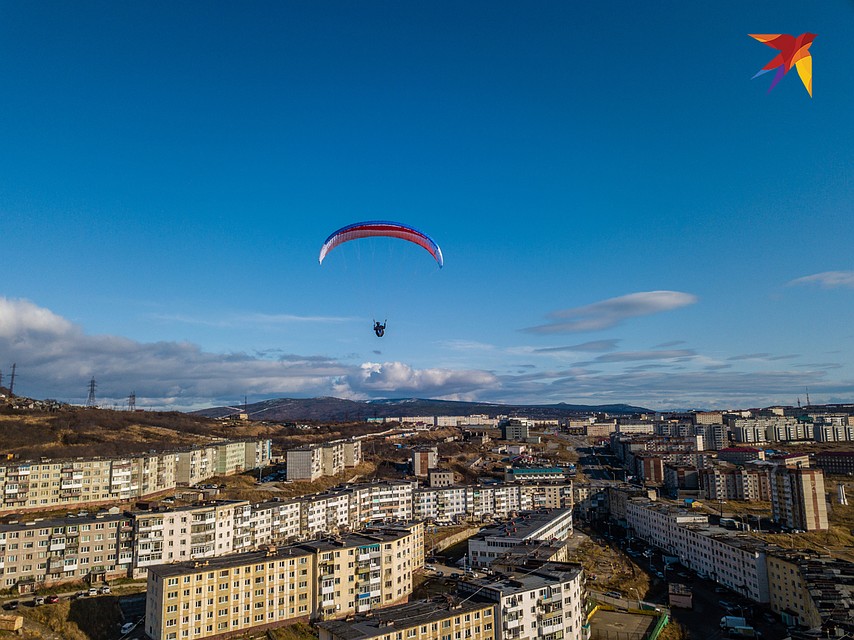 Парапланерист в солнечный день пролетает над Магаданом. Фото: Виктор ГУСЕЙНОВ