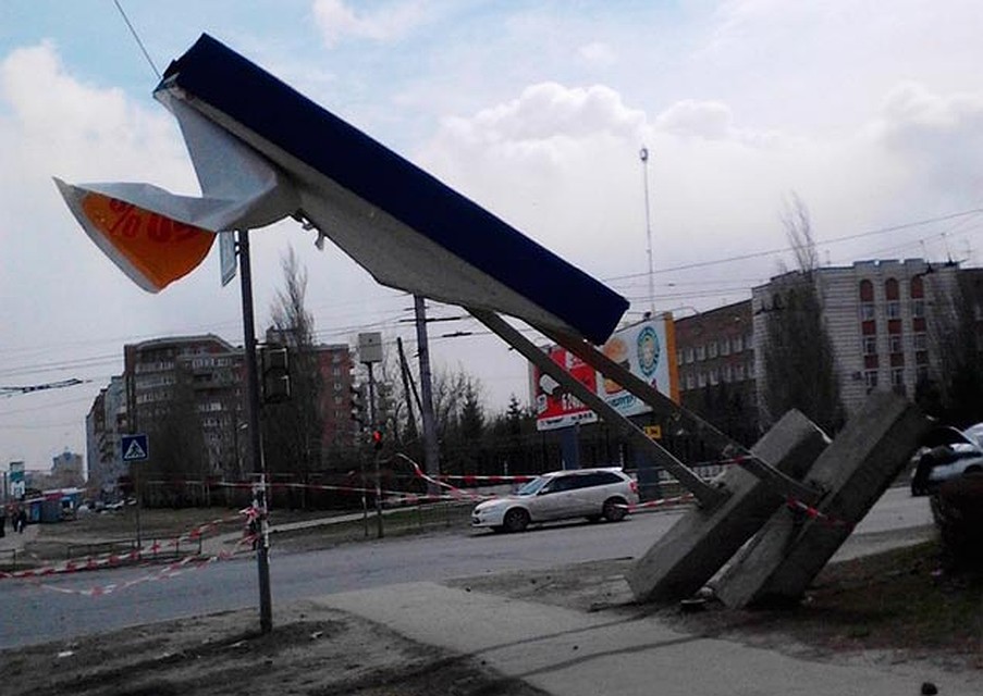 Сильным ветром пригнуло к земле даже рекламный щит, закрепленный на бетонных плитах
