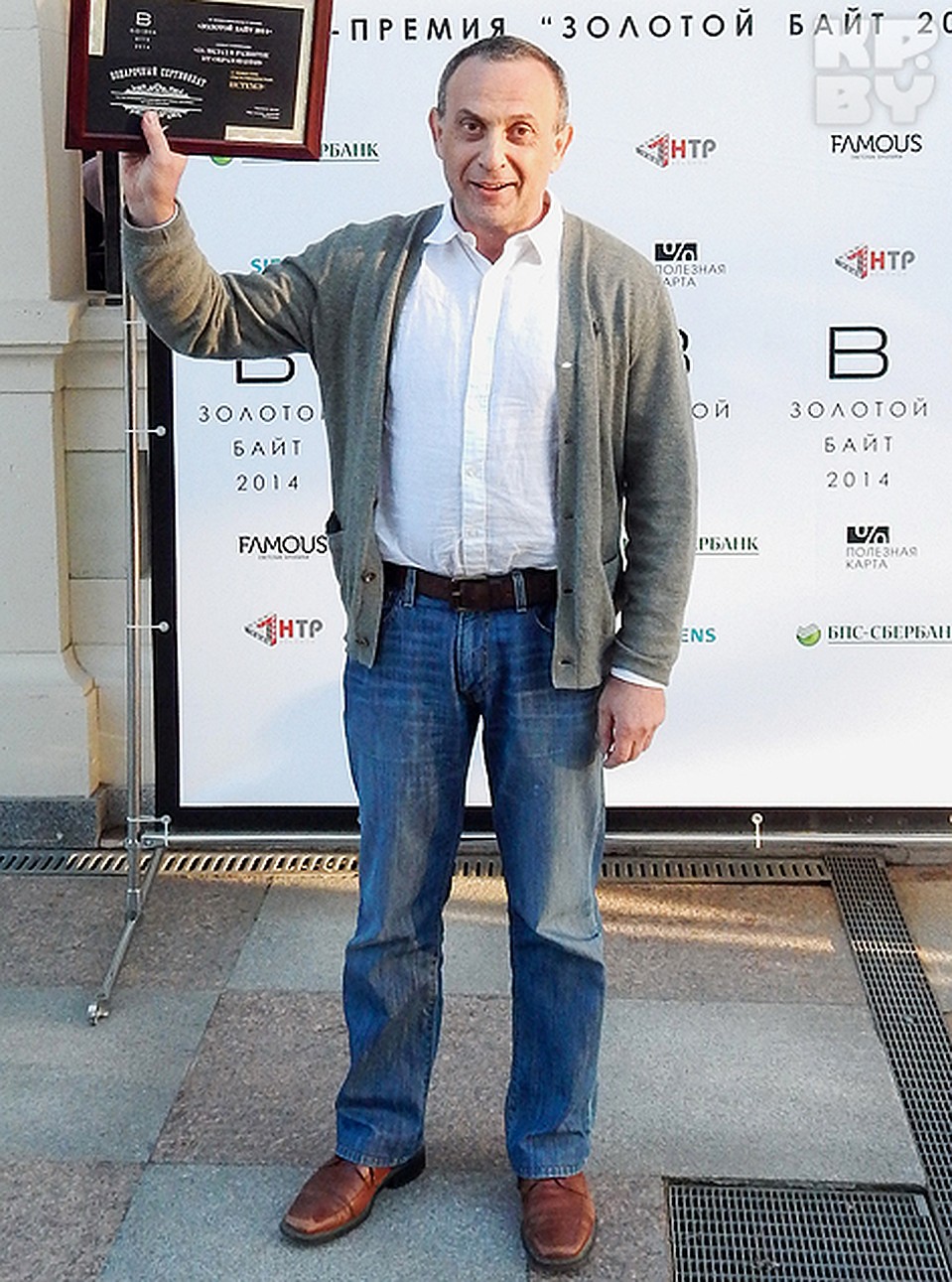 54-летний бизнесмен пришел на церемонию награждения в потертых джинсах, сером свитерке и с черной сумкой через плечо.
