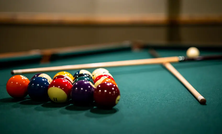A closeup of billiard balls and sticks on the p table