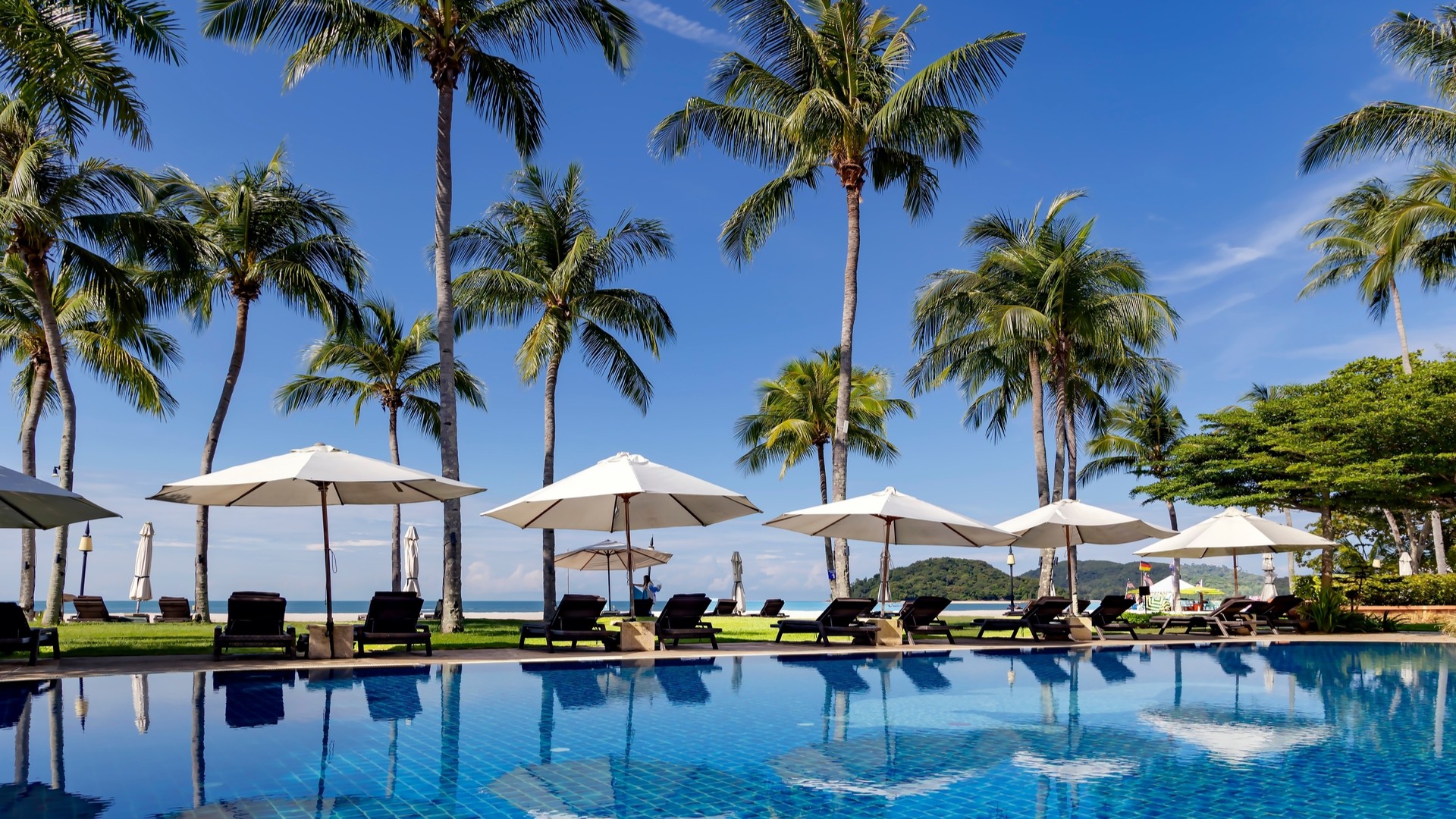 Бассейн в саду с высокими пальмами на территории отеля Casa del Mar Langkawi.